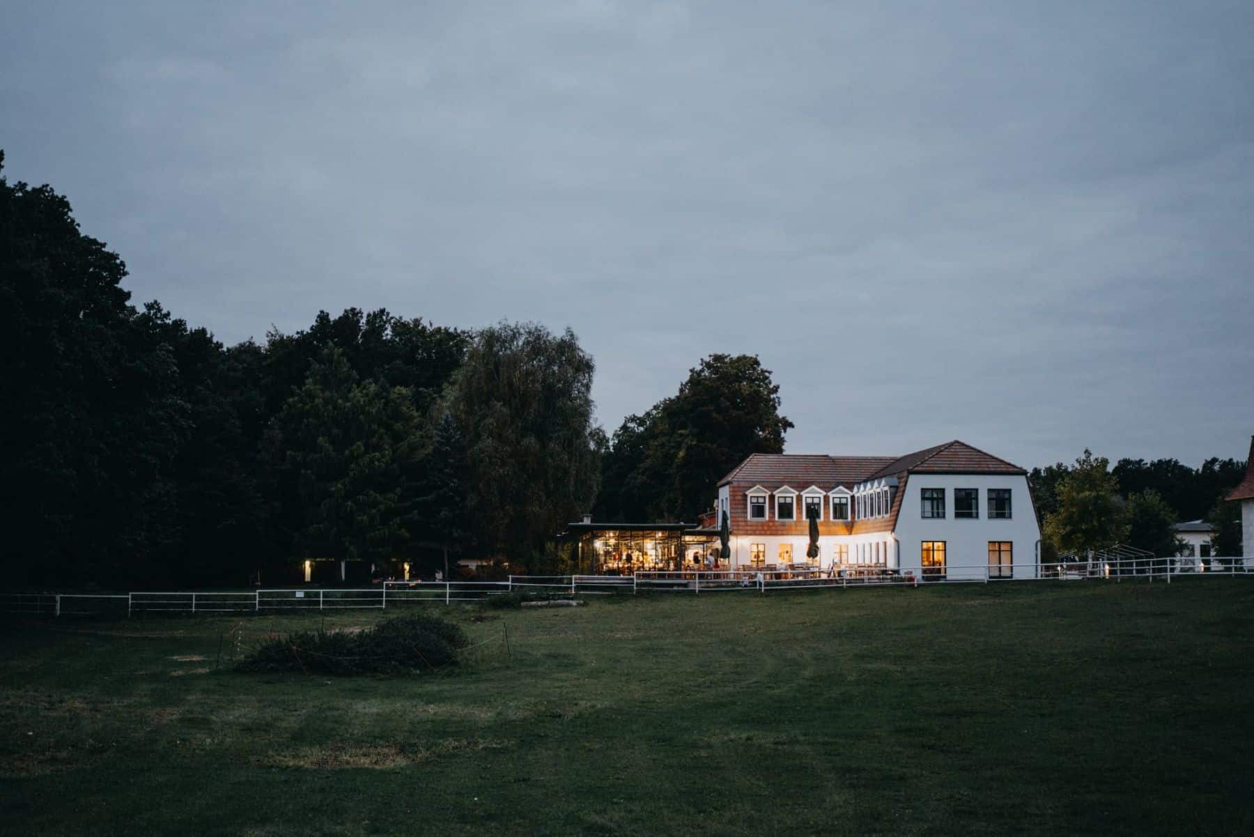 Gut Sarnow am Abend, beleuchtetes Haus an der Wiese